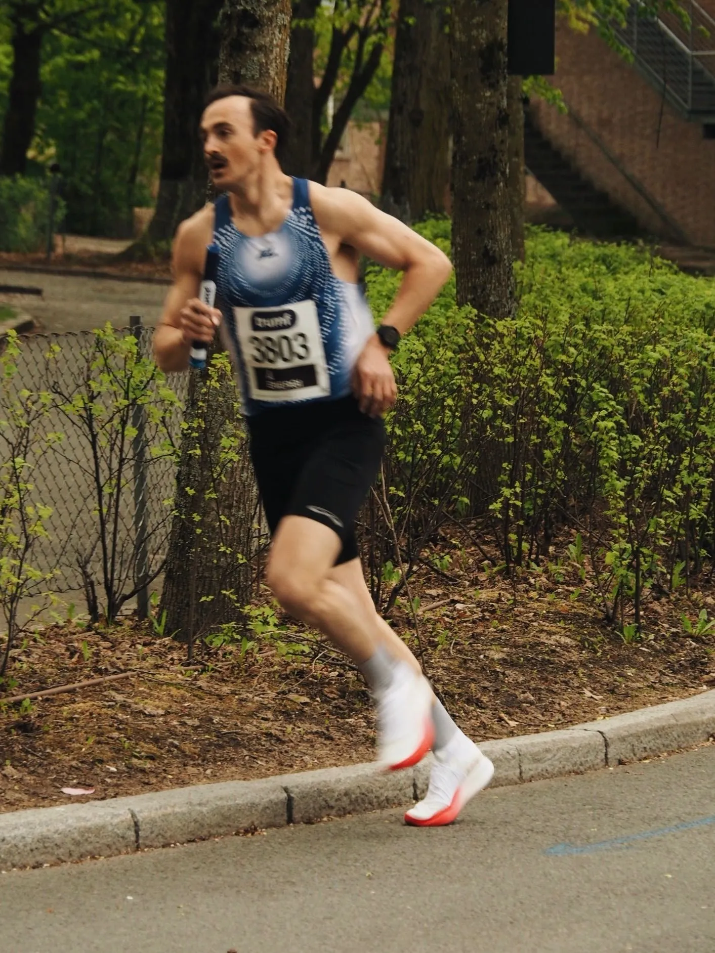 A KL runner in race kit, mid-stride past the spring leaves