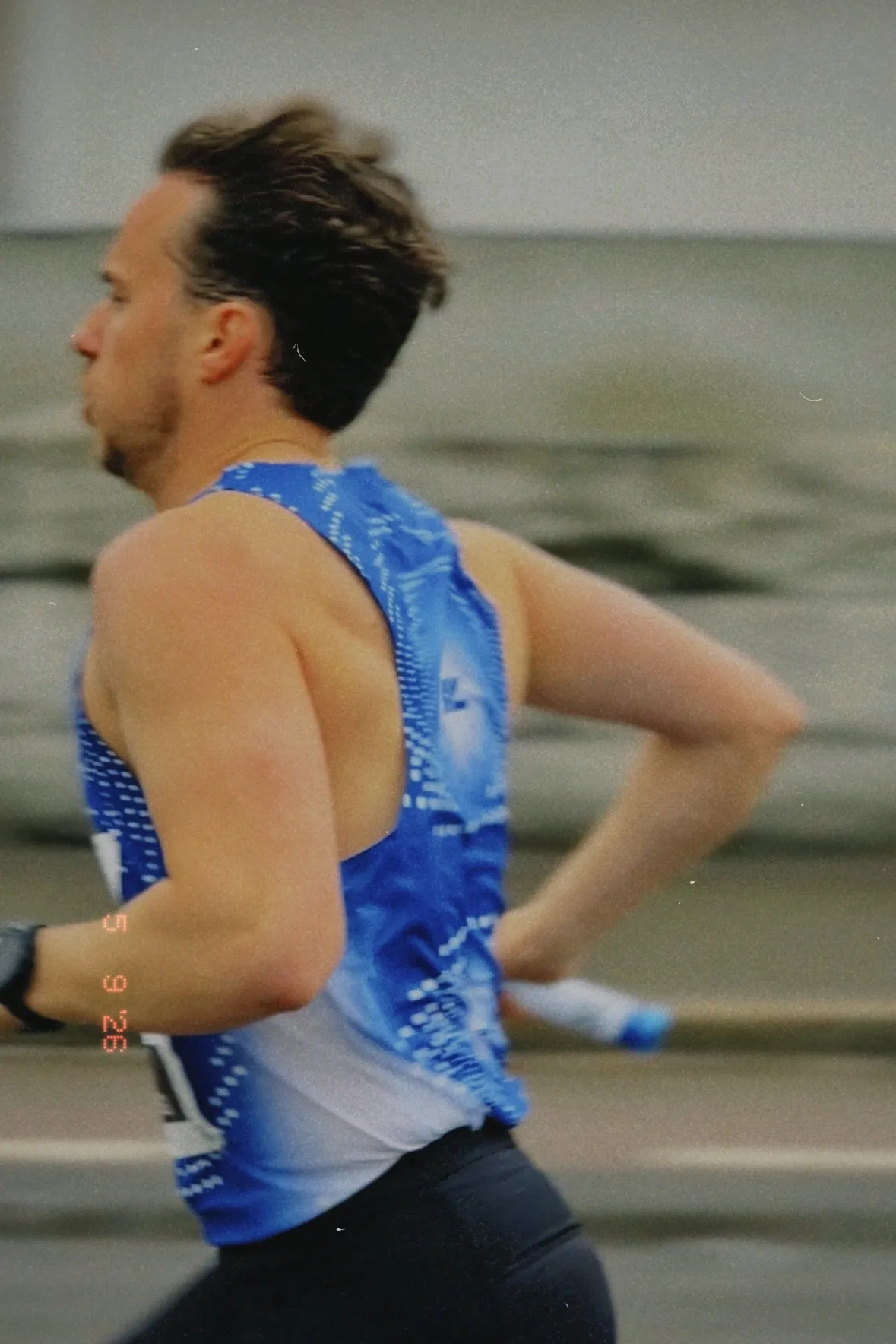 A KL runner mid-leg in a blue race singlet, film-grain action shot
